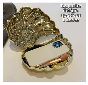 Détail de l'intérieur du sac coquillage doré montrant l'espace pour téléphone et maquillage