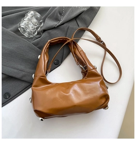 Détail du sac à bandoulière marron caramel clouté avec design souple et rivets argentés