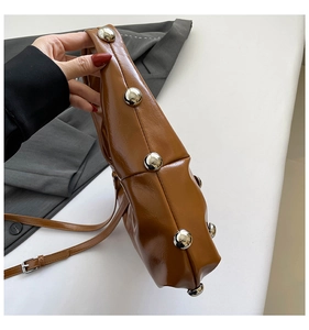 Détail de sac bandoulière en similicuir marron avec clous métalliques sur le côté
