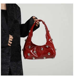 Close-up of a red patent leather hobo bag with silver studs and chic buckle handle