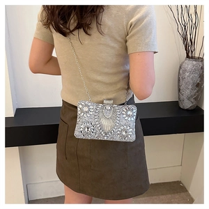 Detailed view of silver rhinestone evening clutch bag with crystal fringe and metal chain