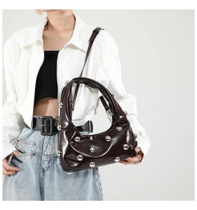 Close-up of dark brown glossy leather shoulder bag with silver dome stud rivets