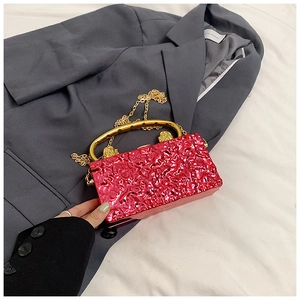 Détail du sac de soirée rose vif avec texture froissée métallique et poignée dorée