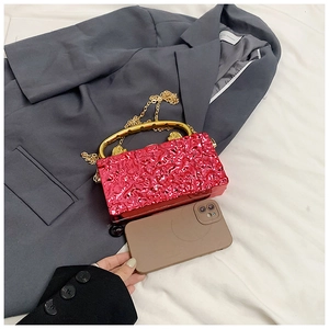 Détail de la pochette en acrylique rouge rose avec poignée dorée et smartphone