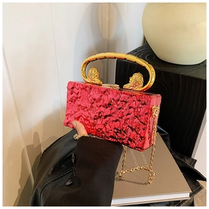 Détail du sac de soirée en acrylique rouge avec poignée tête de lion et texture froissée