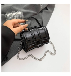 Detailed close-up of a glossy black patent leather mini square bag with silver metal chain