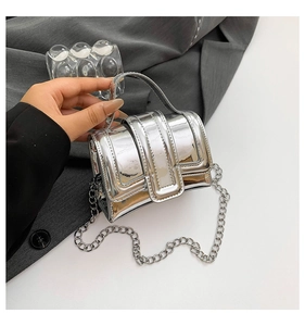 Detail of a mini silver mirror handbag with metallic top handle and chain strap