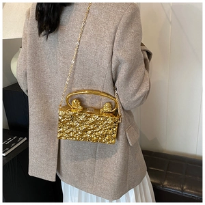 Détail du sac de soirée doré avec texture lave, têtes de lion et bandoulière chaîne