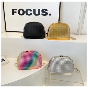 Four metallic shell-shaped clutch bags with chain straps displayed on white stands