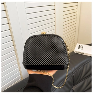 Detail of black bead-textured shell bag with gold clasp and fine metal chain strap