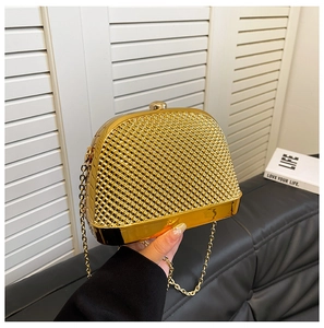 Detail of gold hard-shell evening bag with diamond texture and metallic sphere clasp