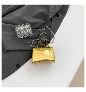 Detail of mini gold metallic handbag with silver chain on grey fashion suit fabric
