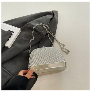 Macro shot of silver shell-shaped evening bag featuring bead embroidery and metal frame