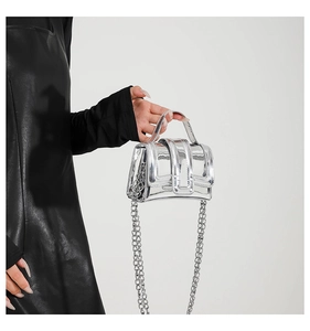 Detail of silver mirror finish mini bag featuring top handle and metallic chain strap
