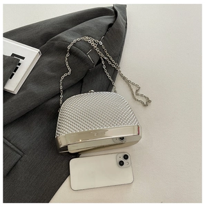 Silver shell-shaped evening bag with metallic texture and chain strap showing phone fit