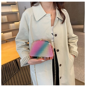 Detail of gradient rainbow evening bag with acrylic chain worn with a trench coat