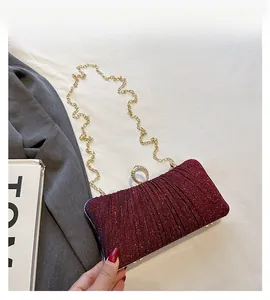 Detail view of burgundy sequined evening bag with golden ring clasp and chain strap