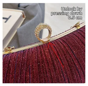 Detail showing how to open the burgundy satin clutch by pressing the crystal ring clasp