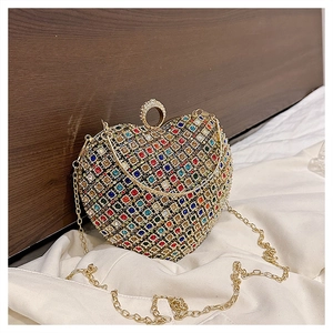Macro shot of heart-shaped evening bag with colorful rhinestones and gold chain