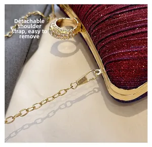 Close-up of wine red sequin evening clutch with detachable gold chain strap detail
