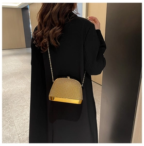Detailed close-up of a gold structured evening bag with metallic mesh and chain strap