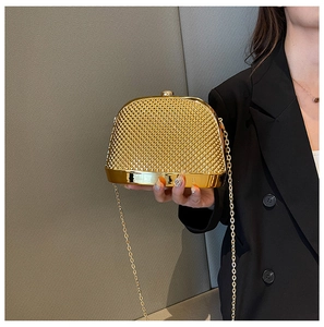 Golden clutch bag with rhombus grid texture and gold chain strap held by a model