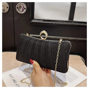 Detail of black pleated evening clutch with sparkling texture and rhinestone ring clasp