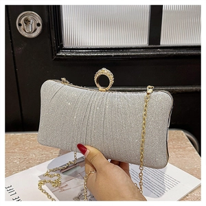 Detail of silver pleated clutch bag with rhinestone ring handle and gold chain strap