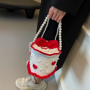 Sac seau tricoté style gâteau avec nœud rouge, anse en perles et motifs au crochet