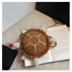 Close-up of a handmade crochet turtle bag resting on a book showing detailed knit texture