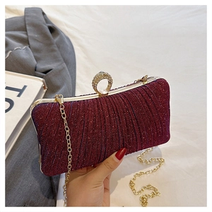 Close-up of wine red glitter clutch with rhinestone ring clasp and gold chain strap