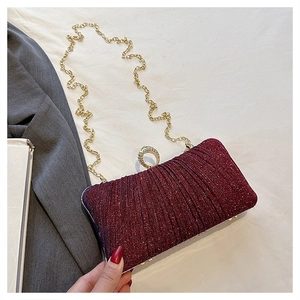 Macro detail of wine red glitter clutch bag with golden chain and diamond buckle