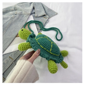 Detail of a handmade crochet turtle shoulder bag with green knit and yellow wavy patterns