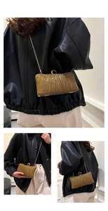 Detail of gold glitter evening clutch with vertical pleats and round ring lock mechanism