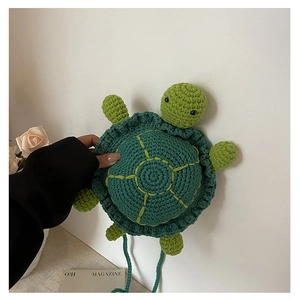 Detail of handmade green knitted turtle bag with shell pattern and crochet strap