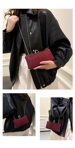 Close-up of wine red pleated evening clutch with gold ring clasp and chain strap