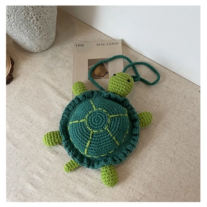Detailed close-up of handmade turtle crochet crossbody bag with knitted texture and strap