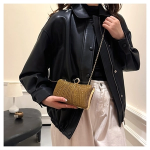 Detail of gold glitter clutch bag with pleated texture and sparkling crystal lock
