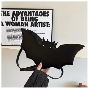 Detail of bat-shaped black PU leather bag with neon green eyes and adjustable strap
