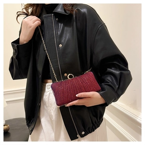 Close-up of a burgundy glitter evening clutch with golden ring clasp and metal chain strap