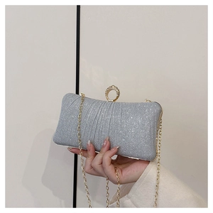 Close-up of a silver glitter evening clutch featuring a rhinestone ring buckle and gold chain