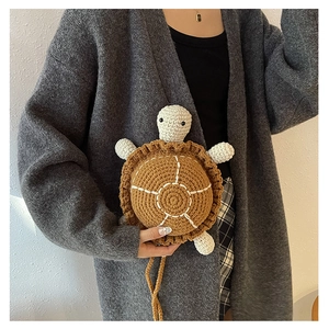 Detail of handmade crochet turtle crossbody bag with brown shell and knitted strap
