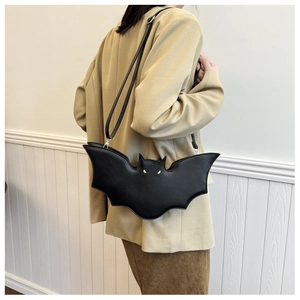 Detail of a black bat-shaped PU leather bag featuring yellow eyes and a sleek shoulder strap