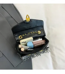 Detailed interior view of quilted crossbody bag with fringe showing phone and lipstick
