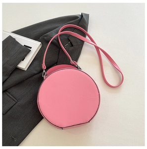 Top view of a creative pink round washing machine style bag on a grey blazer suit