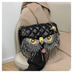 Close-up of owl-shaped quilted bag with silver rhinestone tassels and gold accents