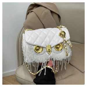 Detail of white quilted owl bag with sparkling rhinestone tassels and gold chain strap