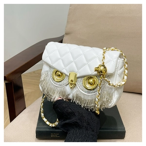 Detail of owl-shaped quilted bag featuring rhinestone tassels and metallic owl eyes