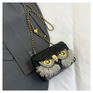 Detail of owl-shaped black quilted shoulder bag with gold metal eyes and fringe lashes