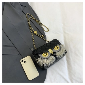 Detail of owl-shaped crossbody bag with glittering rhinestones and long silver tassels